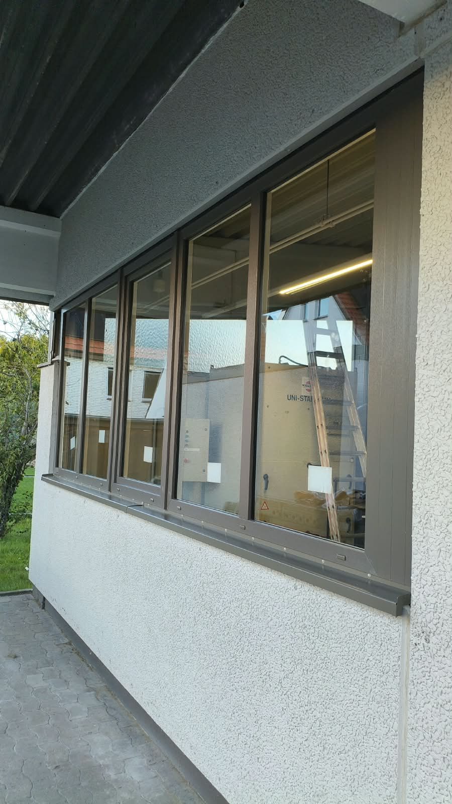 Nová okna v hnědém provedení s parapetem na fasádě provozní budovy v Bielefeldu