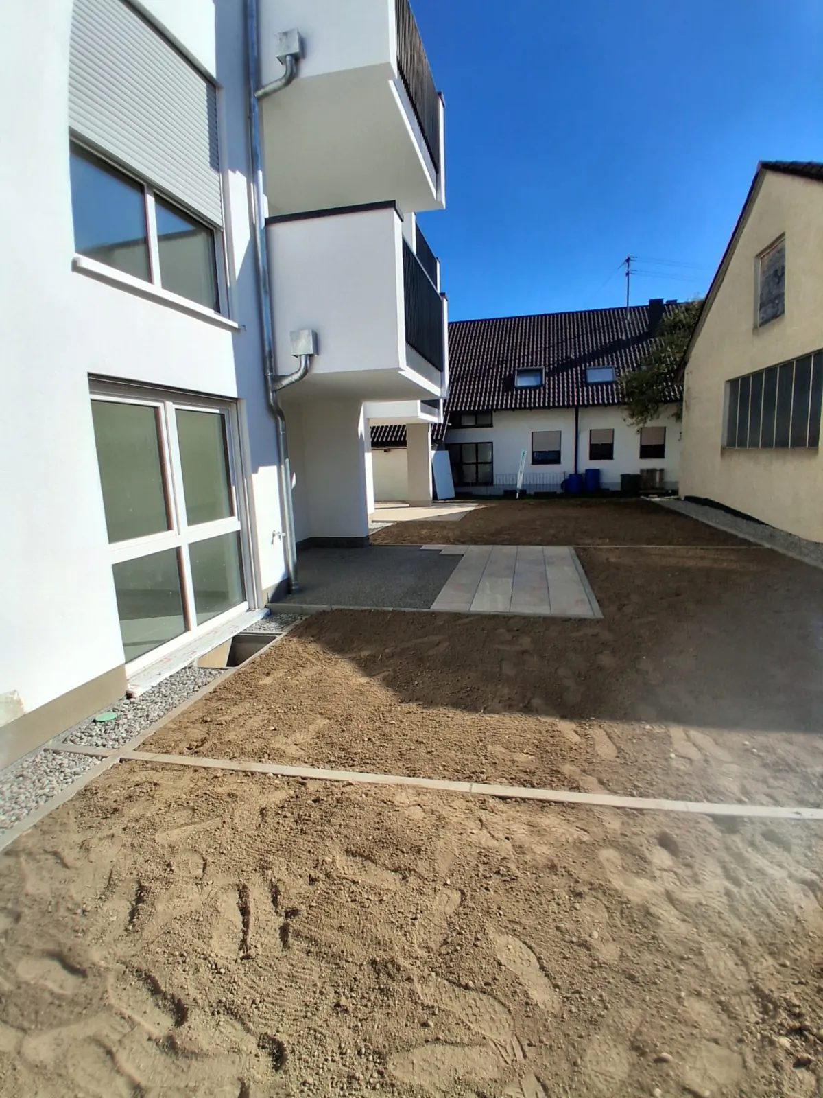 Urovnaný terén, dlažba a obrubníky ve dvoře novostavby bytového domu
